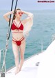 A woman in a red bikini standing on a boat.