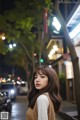 A woman standing in the middle of a city street at night.