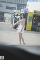 A woman in a white skirt is standing in the middle of the street.