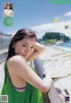 A woman in a green dress leaning on a railing.