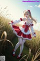 A woman in a red and white dress standing in a field.