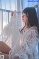 A woman in a white robe sitting on a window sill.