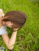 A woman laying in the grass with her head in her hands.