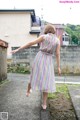 A woman in a striped dress is walking down the street.