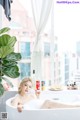 A woman sitting in a bathtub next to a window.