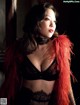 A woman wearing a black bra and a red feather boa.