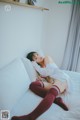 A woman laying on a bed in a white shirt and red stockings.