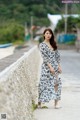 A woman in a black and white dress standing on a sidewalk.