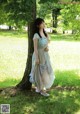 A woman standing next to a tree in a park.