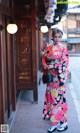 A woman in a pink and black kimono standing in front of a building.