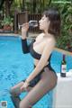 A woman sitting by a pool drinking a glass of wine.