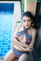 A woman in a colorful bikini sitting by a pool.