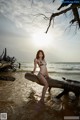 A woman in a bikini sitting on a log in the water.