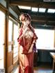 A woman in a red kimono standing in a room.