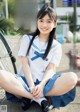 A young woman in a school uniform sitting on the ground.